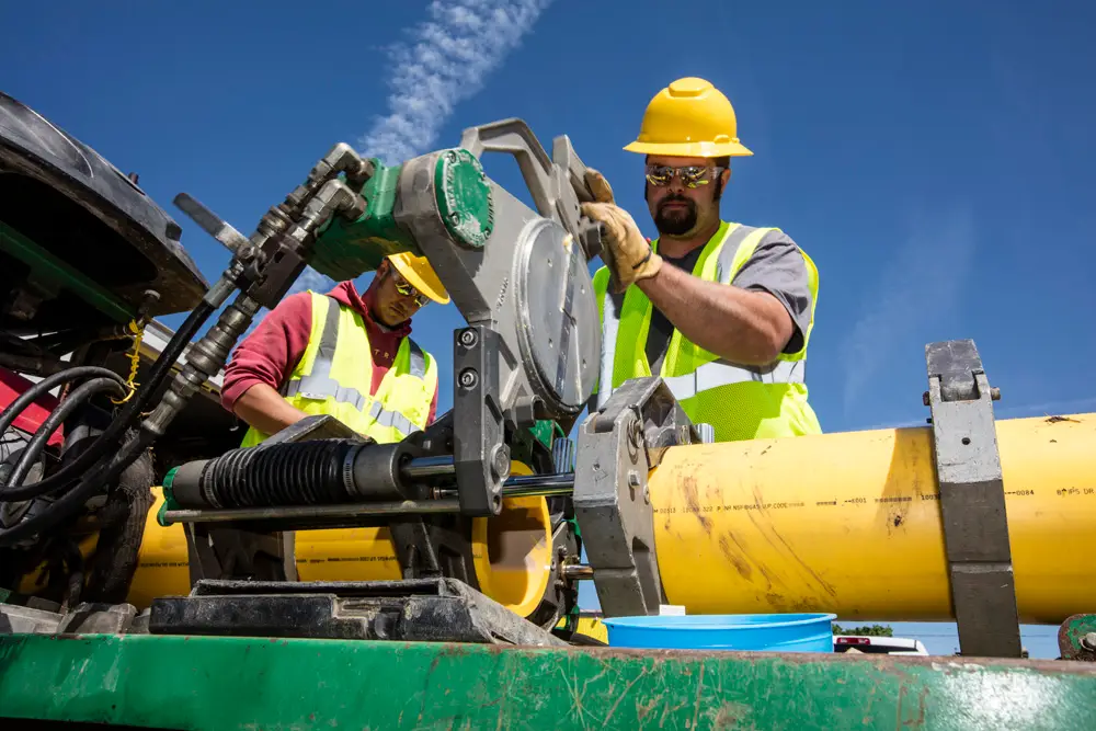 Laborers cutting a pipe