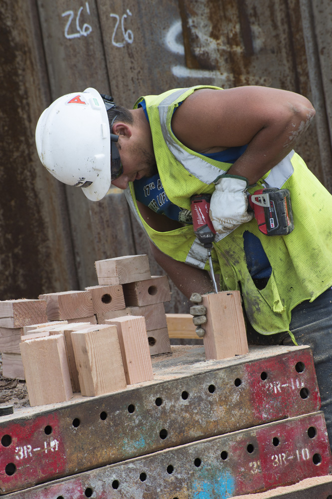 Laborer drilling holes in blocks of wood